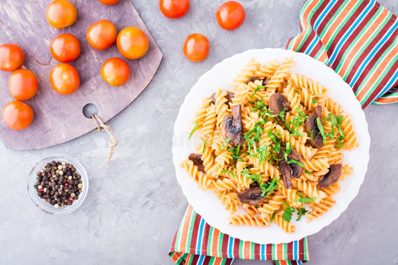 Appetizing pasta with fried mushrooms, tomato and fresh herbs royalty free stock image