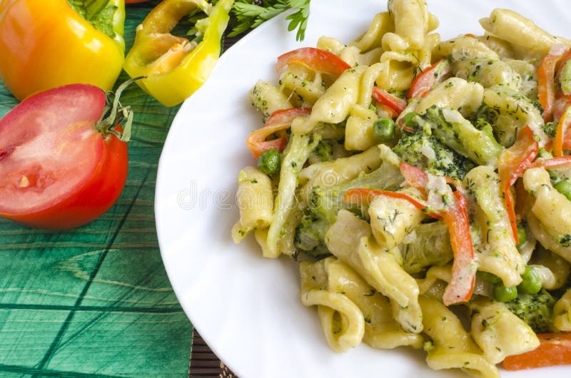 Appetizing pasta with vegetables and cheese on a white plate close-up stock images