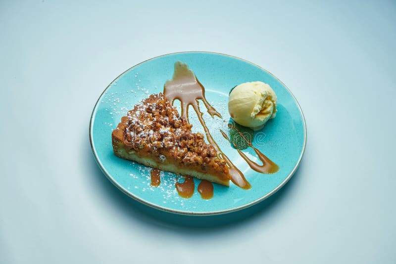 Appetizing pumpkin pie with caramel and vanilla ice cream on a blue plate isolated on grey background. Delicious pastries stock photos Appetizing pumpkin pie with caramel and vanilla ice cream on a blue plate isolated on grey background. Delicious pastries stock photos