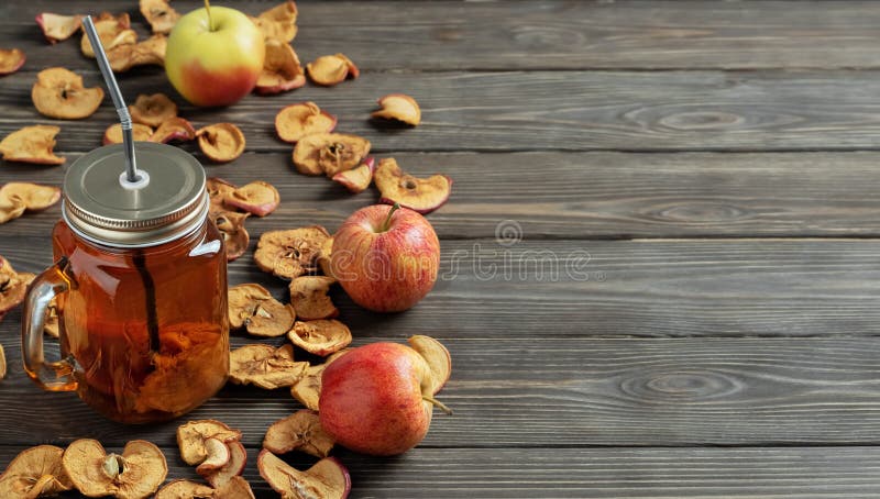 The apple cider or compote stewed apple drink , in the glass mugs with straws. Dried apples and ripe apples on a dark wooden stock photos The apple cider or compote stewed apple drink , in the glass mugs with straws. Dried apples and ripe apples on a dark wooden stock photos