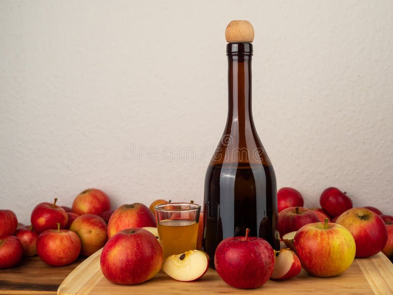 Apple Cider Vinegar in a Bottle with Apples Against a White Wall. Stock