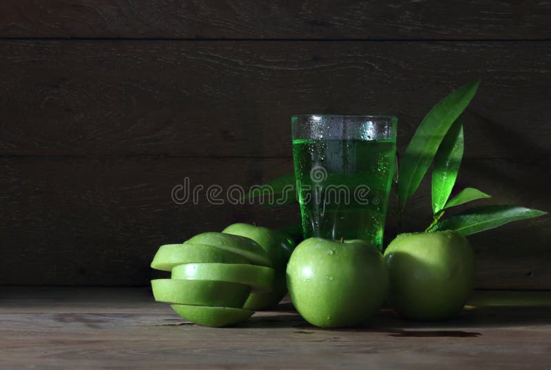 Apple juice with many green apples with drops of water. Apple juice with many green apples with drops of water, leaves on the old wooden table stock photo Apple juice with many green apples with drops of water. Apple juice with many green apples with drops of water, leaves on the old wooden table stock photo