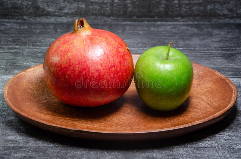 Apple och granatäpple på en träbunke royaltyfria foton Apple och granatäpple på en träbunke royaltyfria foton