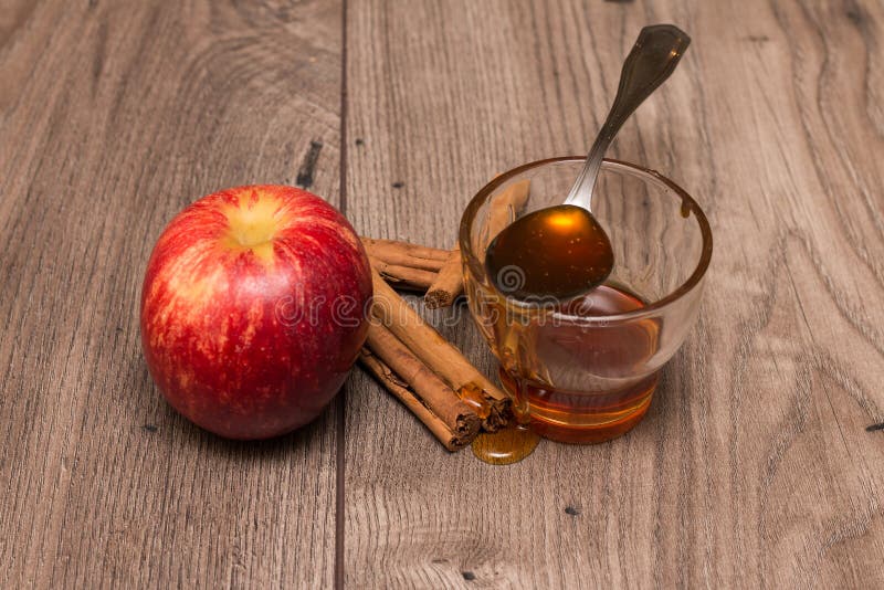 Apple, palillos de canela, y un vidrio con la miel imagen de archivo libre de regalías Apple, palillos de canela, y un vidrio con la miel imagen de archivo libre de regalías