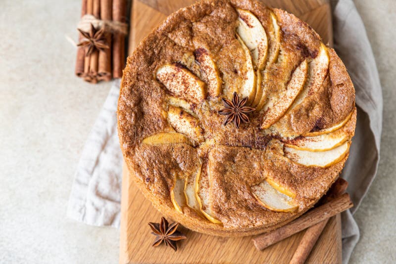 Apple pie with cinnamon on wooden board, light concrete background. Semolina cake with apple and spices. Homemade mannik