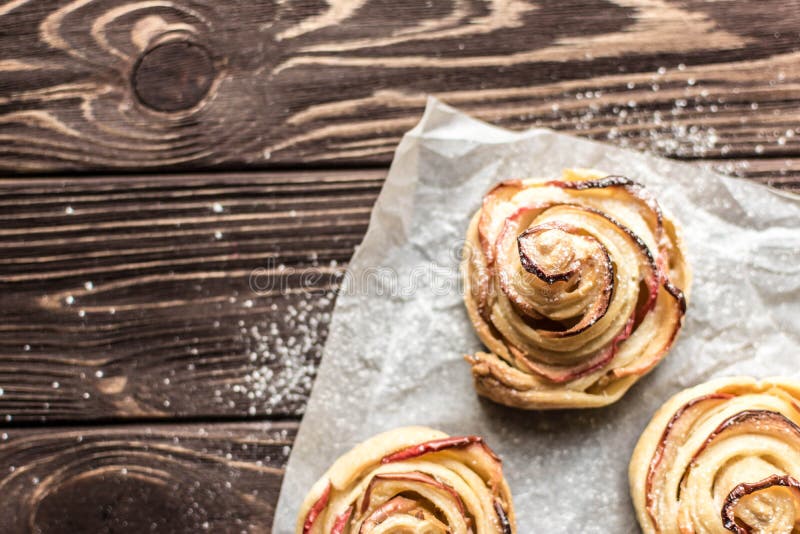Apple rose puff pastries sprinkled with powdered on baking paper