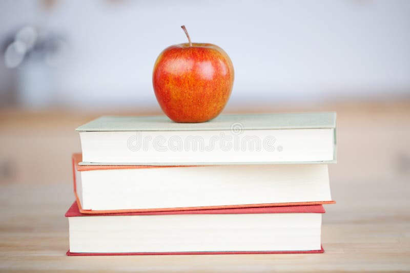 Apple rosso sui libri impilati sulla Tabella immagine stock libera da diritti Apple rosso sui libri impilati sulla Tabella immagine stock libera da diritti