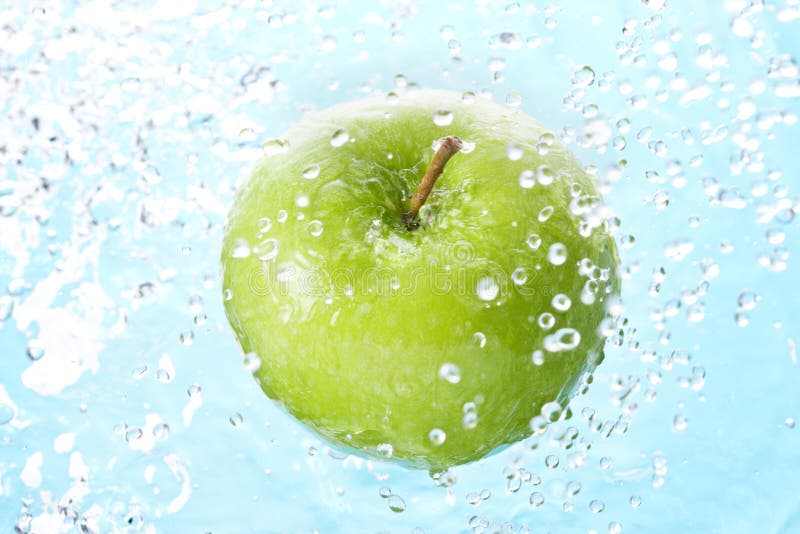 A green apple with water spray and a light blue tone. A green apple with water spray and a light blue tone