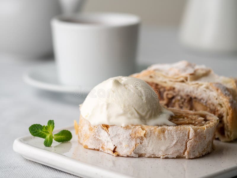 Apple strudel with ice cream and cinnamon. Baked cake and tea, delicious dessert on the table. Side view, close-up