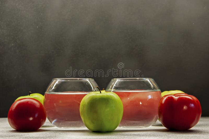 Photo apples green and red tomatoes with two glasses on mixed background stock photography