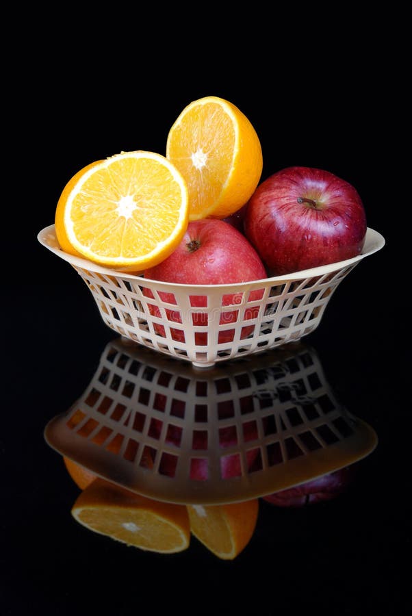 Apples and oranges in a basket with black background
