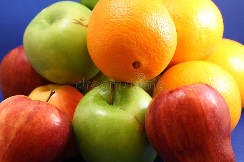 Nice collection of apples and oranges in vivid colors isolated against a blue background. Nice collection of apples and oranges in vivid colors isolated against a blue background