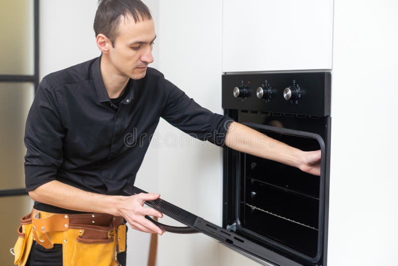 Appliance Repair. Man Installing Electricity Oven in the Kitchen Stock