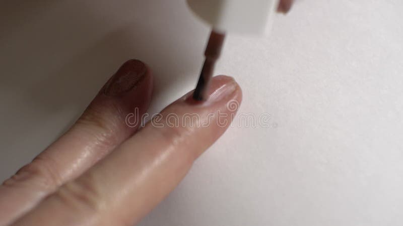 Application d'une manucure sur les doigts de la main droite d'une femme âgée. fond blanc. gros plan sur les doigts banque de vidéos