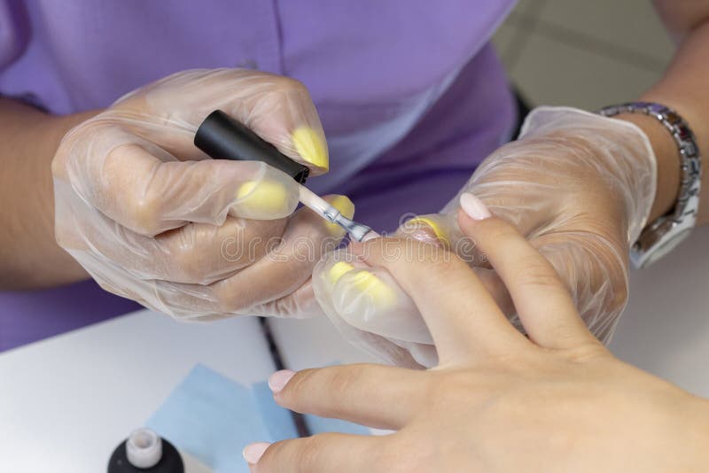 Application du poli de gel sur les ongles shellac le manucure fait la manucure dans le salon vernis naturel de couleur tonalité n photo stock Application du poli de gel sur les ongles shellac le manucure fait la manucure dans le salon vernis naturel de couleur tonalité n photo stock