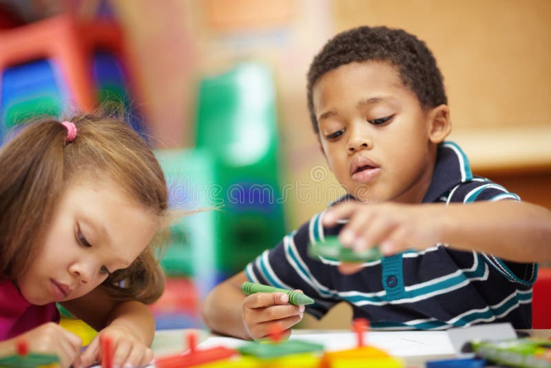 Apprendimento e sviluppo. bambini e ragazze dell'asilo scarabocchiano e disegnano con pastelli multicolori nell'asilo immagine stock libera da diritti