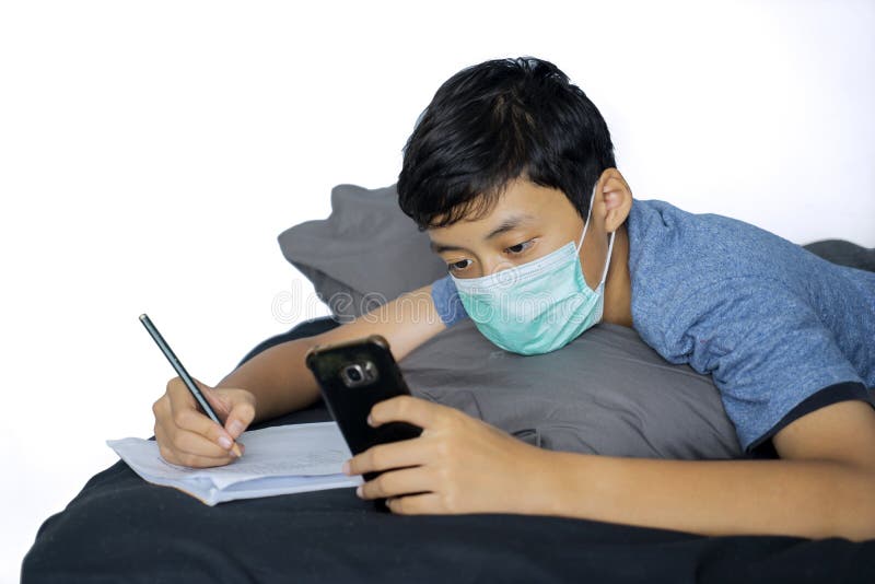 Apprentissage écolier avec le portable sur le lit photo libre de droits