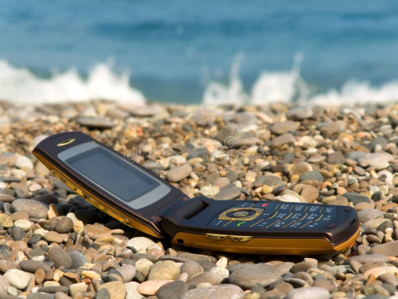 Apra il telefono mobile sulla spiaggia immagine stock Apra il telefono mobile sulla spiaggia immagine stock