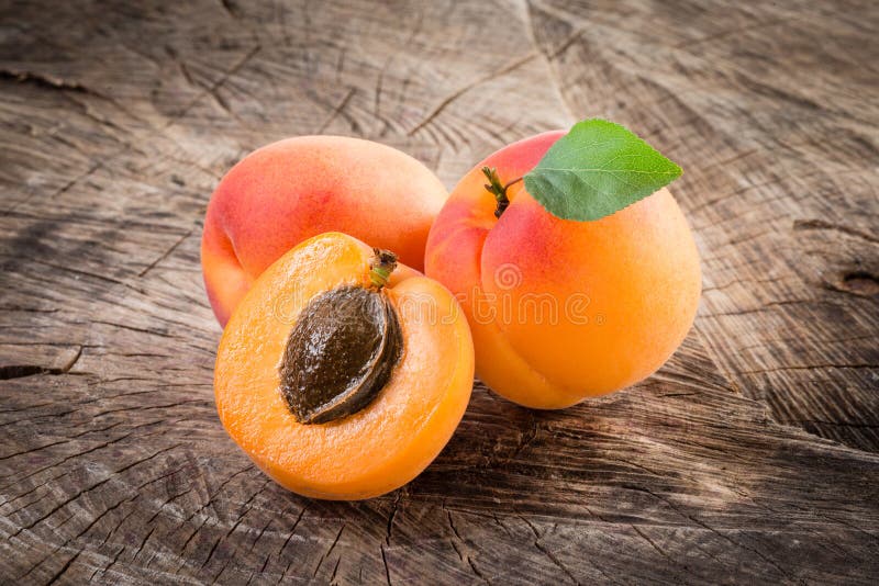 Apricots with leaves on wooden background