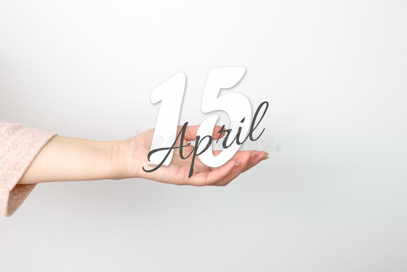 April 15th. Day 15 of month, Calendar date. Calendar Date floating over female hand on grey background. Spring month, day of the stock photo
