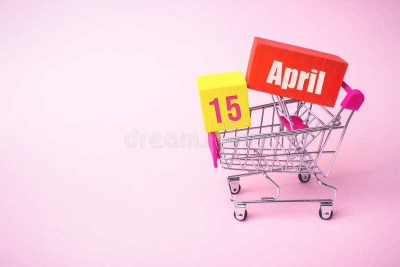 April 15th. Day 15 of month, Calendar date. Close up toy metal shopping cart with red and yellow box inside with Calendar date on stock photography