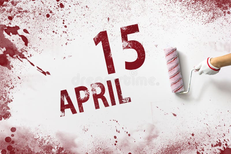 April 15th. Day 15 of month, Calendar date. The hand holds a roller with red paint and writes a calendar date on a white stock photos
