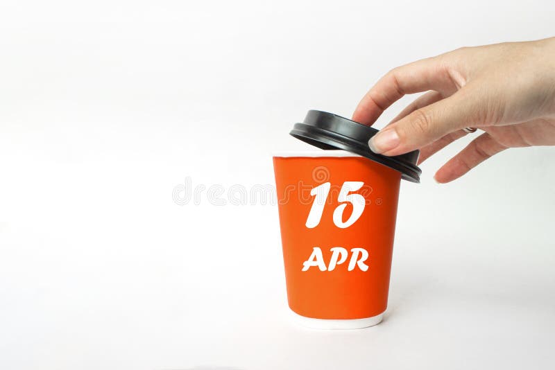 April 15th. Day 15 of month, Calendar date. A woman`s hand open black plastic cap of red disposable cardboard coffee paper cup royalty free stock image.