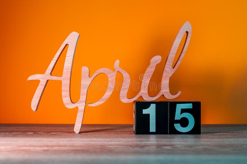 April 15th. Day 15 of month, calendar on wooden table and green background. Spring time, empty space for text royalty free stock images