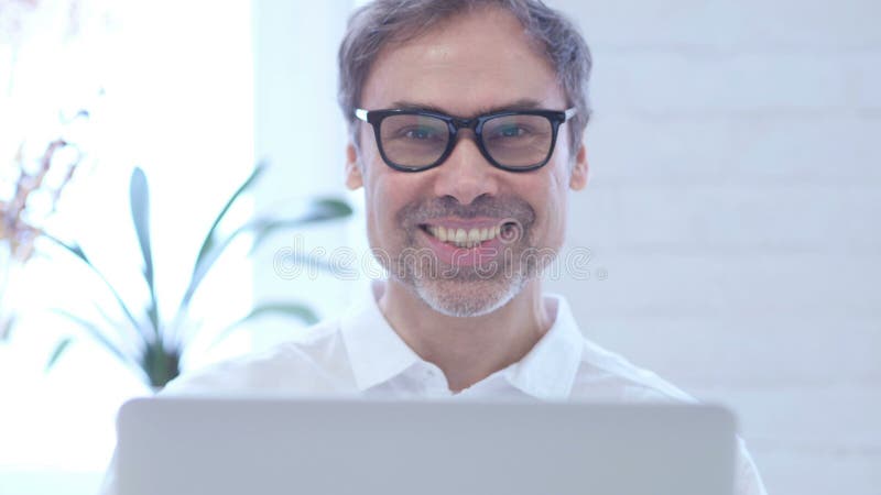 Aprobaty w średnim wieku mężczyzną pracuje na laptopie, zakończenie w górę zbiory Aprobaty w średnim wieku mężczyzną pracuje na laptopie, zakończenie w górę zbiory