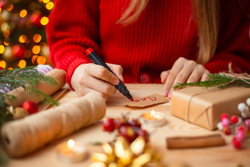 Apropiați mâinile unei fete care semnează cadoul de Crăciun stock image