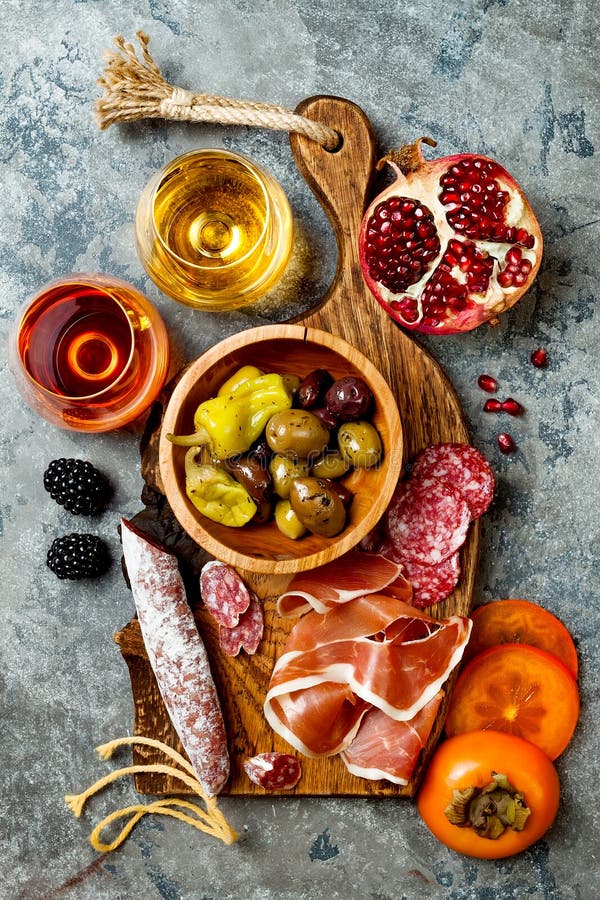 Aptitretare bordlägger med italienska antipastimellanmål och vin i exponeringsglas Charkuteribräde över grå färgbetongbakgrund To arkivbilder Aptitretare bordlägger med italienska antipastimellanmål och vin i exponeringsglas Charkuteribräde över grå färgbetongbakgrund To arkivbilder