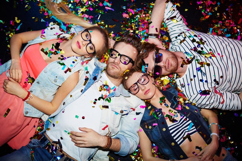 Young friends sleeping in confetti on the floor in nightclub after party. Young friends sleeping in confetti on the floor in nightclub after party