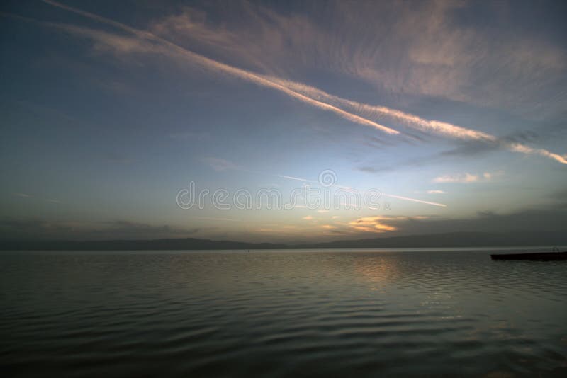Após o por do sol sobre o lago Ohrid com nuvens e traços coloridos de avião fotografia de stock royalty free Após o por do sol sobre o lago Ohrid com nuvens e traços coloridos de avião fotografia de stock royalty free