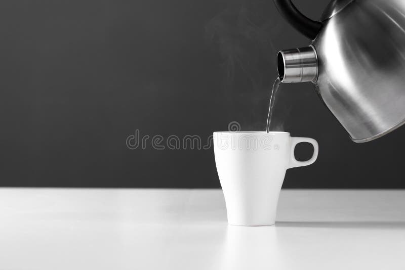 Apă de tip retro cetonă turnată într-o cupă pe fond alb cu fum pe masa din lemn royalty free stock photography