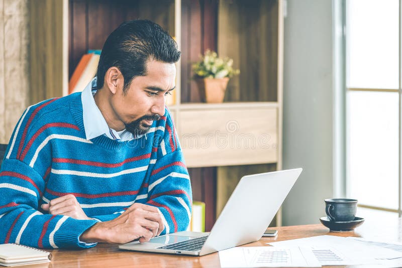 Arab businessman in casual clothes working in the office with laptop, paper, note and a cup of coffee on working table stock image Arab businessman in casual clothes working in the office with laptop, paper, note and a cup of coffee on working table stock image