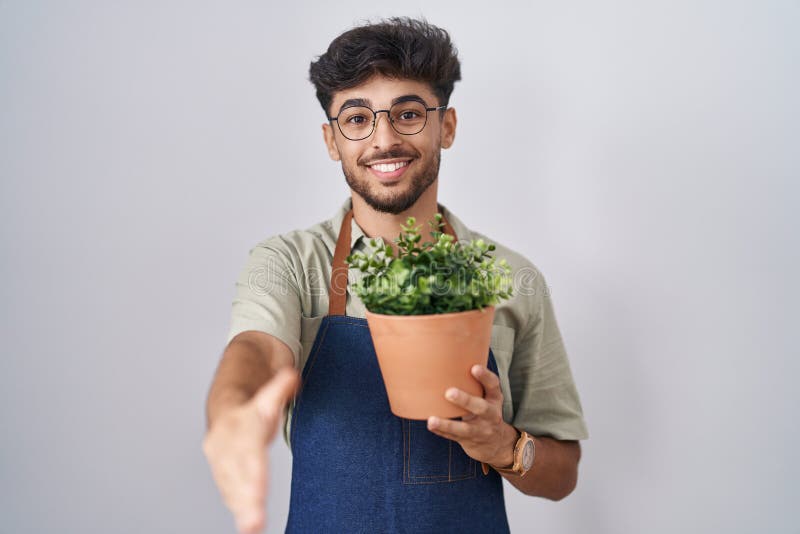 Arab Man with Beard Holding Green Plant Pot Smiling Friendly Offering