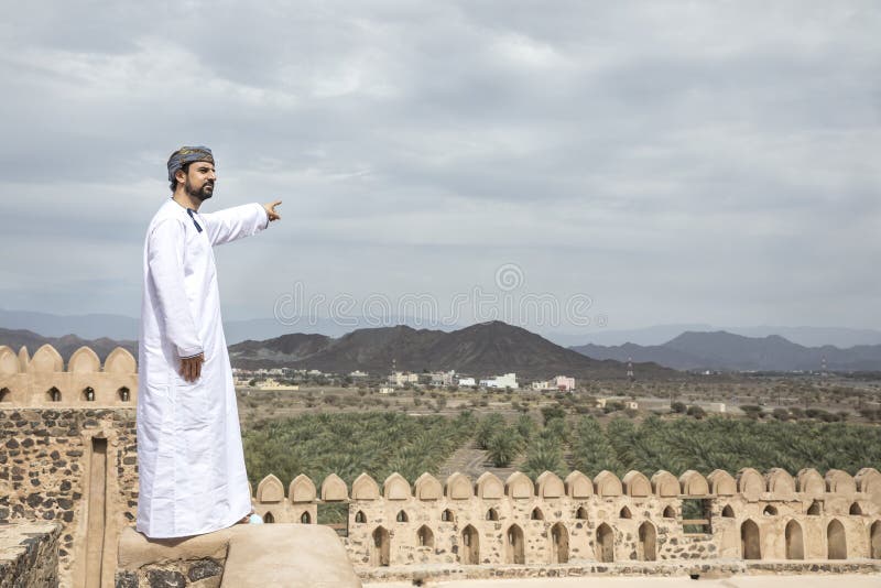 Arab man in traditional omani outfit pointing to the distance