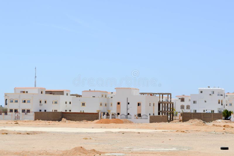 Arabian rectangular houses in the desert with windows against the background of yellow sand and the blue sky. stock images
