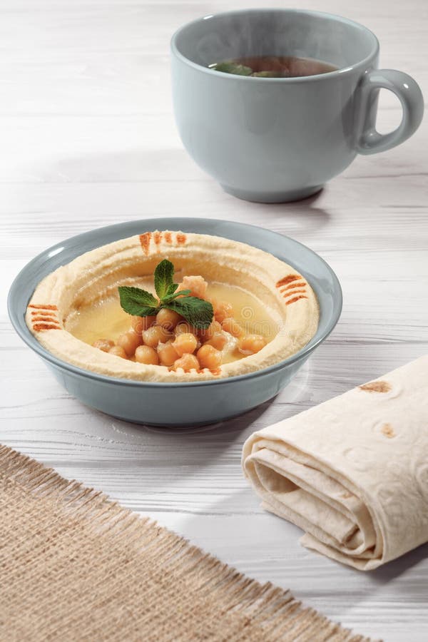 Arabic Breakfast Hummus Dish with Bread and Cup of Hot Mint Tea on