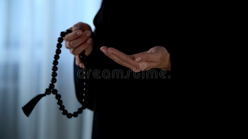 Arabische Frau im hijab, das in der Hand Gebete durch Rosenbeet, religiöses Verzeihen zählt