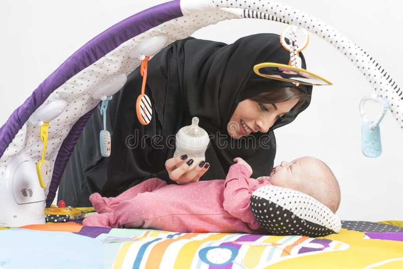 Arabische Mutter, die ihr Baby auf einer Spielmatte einzieht stockbild Arabische Mutter, die ihr Baby auf einer Spielmatte einzieht stockbild
