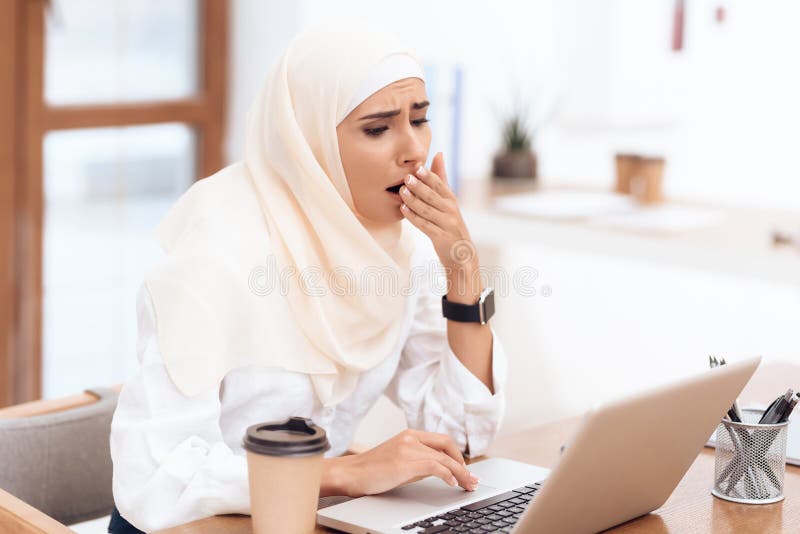 Arabische vrouw die die een headscarfzitting dragen op het werk wordt vermoeid stock afbeeldingen Arabische vrouw die die een headscarfzitting dragen op het werk wordt vermoeid stock afbeeldingen