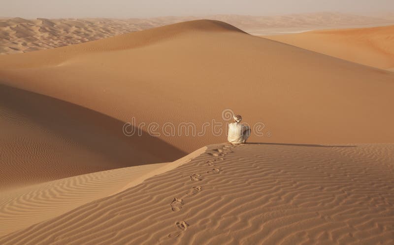 Arabischer Mann in der traditionellen Ausstattung, die in der arabischen Wüste sitzt und die Landschaft genießt