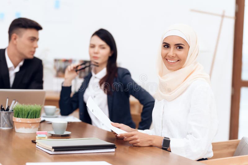 Arabska kobieta w hijab pracuje w biurze wraz z jej kolegami obraz royalty free Arabska kobieta w hijab pracuje w biurze wraz z jej kolegami obraz royalty free