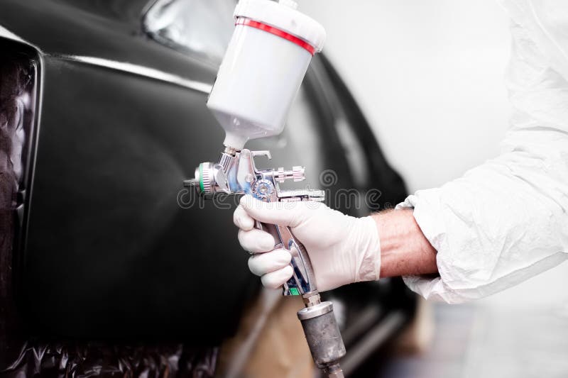 Arbeider die een verfspuitpistool voor het schilderen van een auto gebruiken royalty-vrije stock fotografie Arbeider die een verfspuitpistool voor het schilderen van een auto gebruiken royalty-vrije stock fotografie