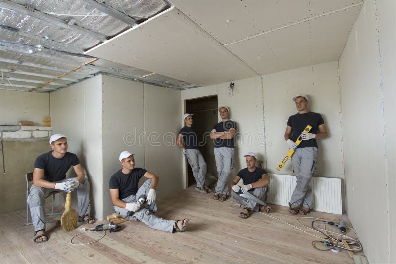 Arbeiders in ruimte met aluminiumfolie op muren en plafond en drywall Wederopbouw en isolatie stock afbeelding Arbeiders in ruimte met aluminiumfolie op muren en plafond en drywall Wederopbouw en isolatie stock afbeelding