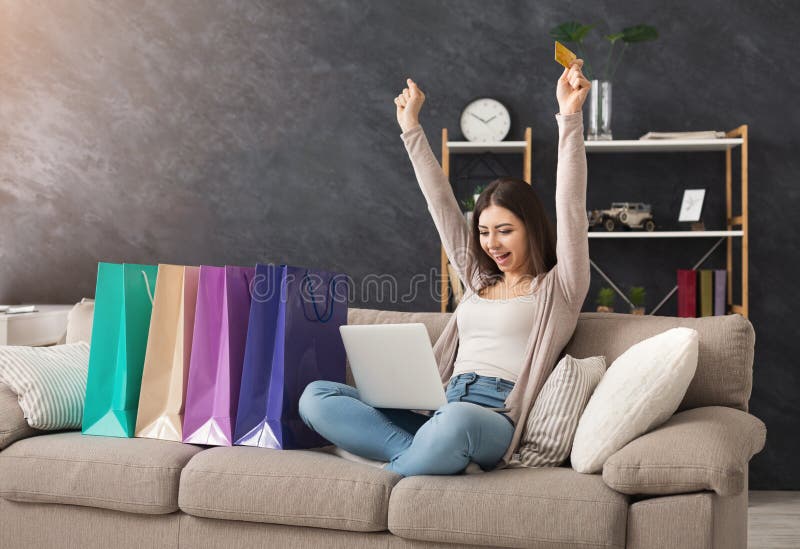 Happy fashion woman buying online with laptop and credit card, with colorful shopping bags beside, copy space. Happy fashion woman buying online with laptop and credit card, with colorful shopping bags beside, copy space