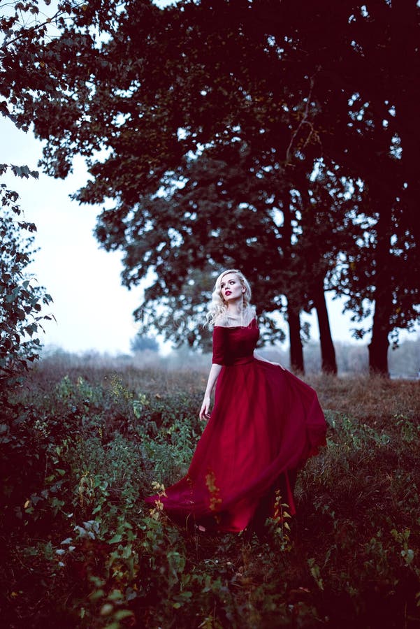 Arbeiten Sie herrliche junge Blondine im schönen roten Kleid in einer Märchenwaldmagieatmosphäre um Retouched Schuss tonend stockfotos Arbeiten Sie herrliche junge Blondine im schönen roten Kleid in einer Märchenwaldmagieatmosphäre um Retouched Schuss tonend stockfotos