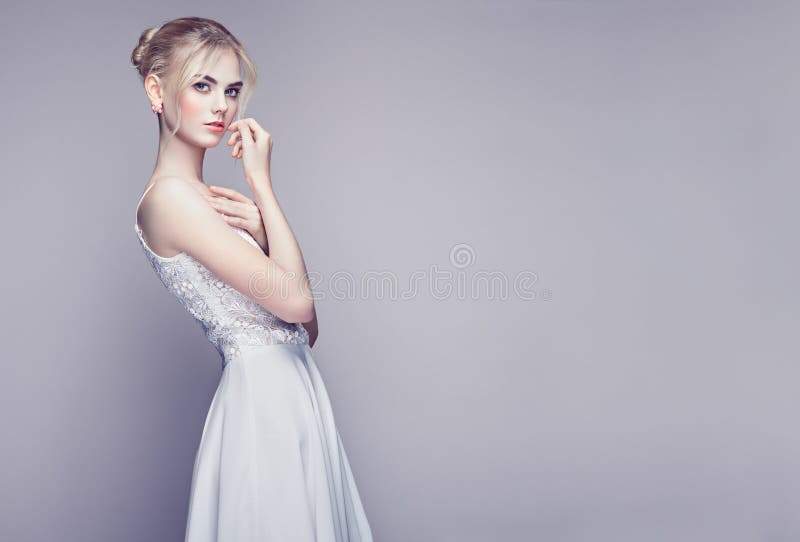 Fashion portrait of Beautiful Young Woman with Blond Hair. Girl in white Dress on White Background. Fashion portrait of Beautiful Young Woman with Blond Hair. Girl in white Dress on White Background