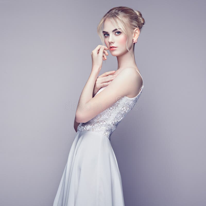 Fashion portrait of beautiful young woman with blond hair. Girl in white dress on white background. Fashion portrait of beautiful young woman with blond hair. Girl in white dress on white background